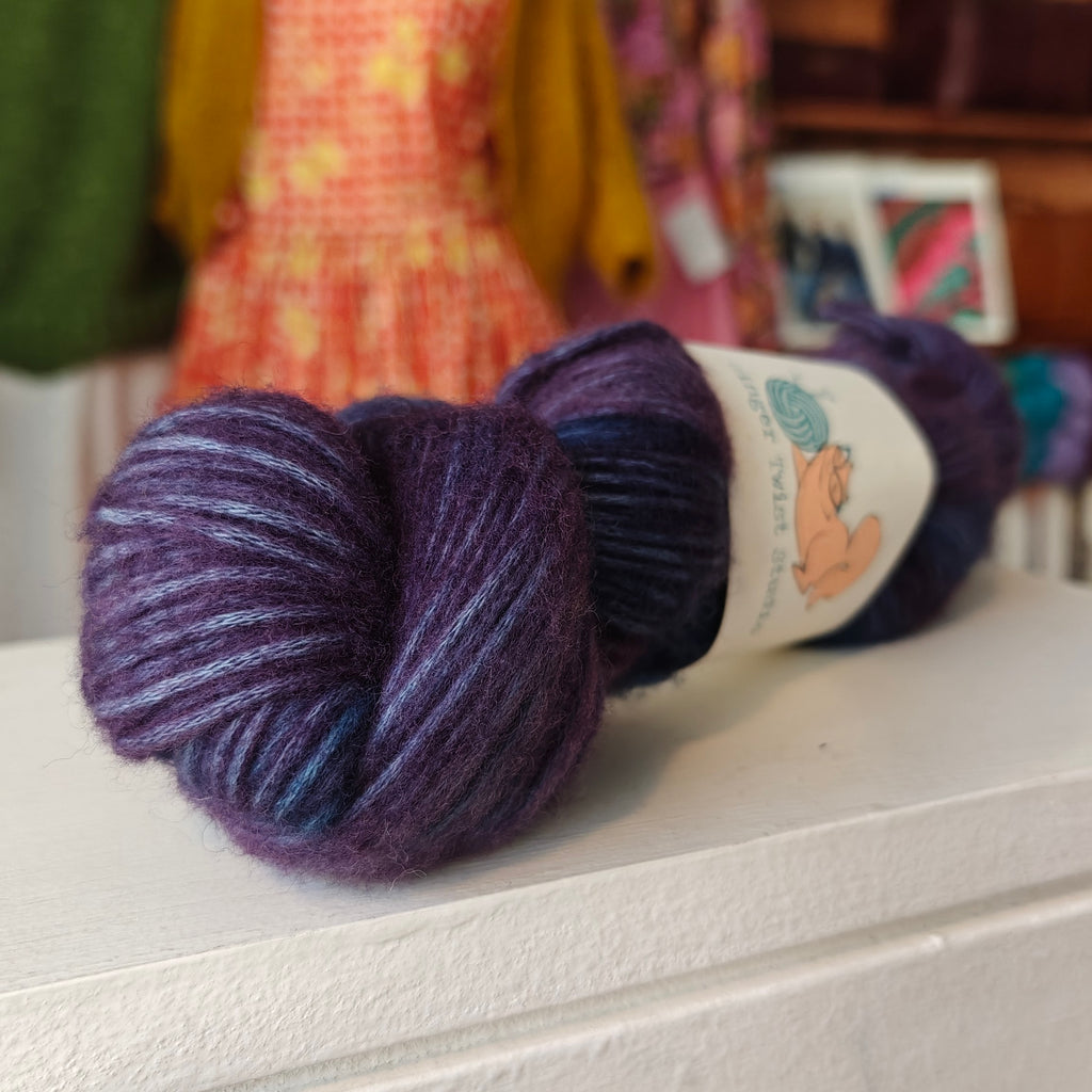 Purple yarn skein with a label on a white surface