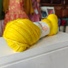 Yellow yarn ball with a label on a white surface