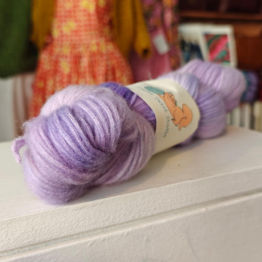 Ball of purple yarn with a label on a white surface
