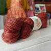 Red skein of yarn with a label on a white surface, blurred background