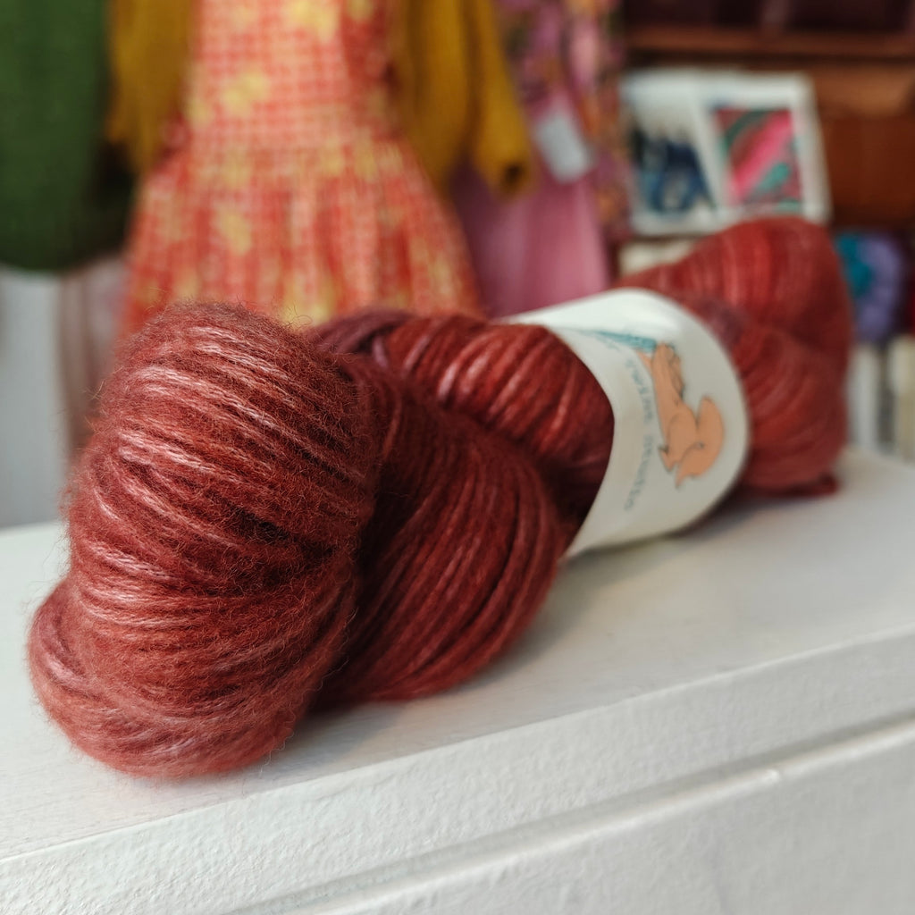 Red skein of yarn with a label on a white surface, blurred background