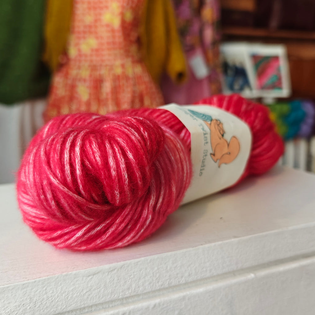 Red skein of yarn with a label on a white surface, blurred background
