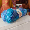 Two blue skeins of yarn on a white surface with a blurred background