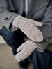 Close-up of a person wearing gray knitted gloves with a blurred background