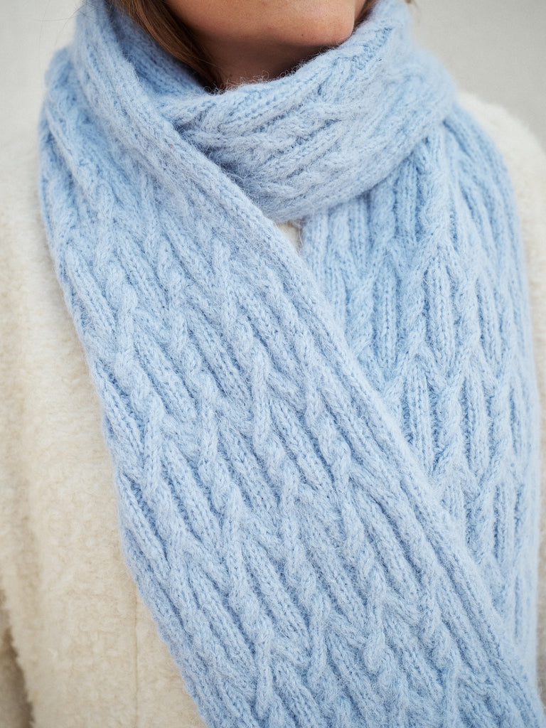 Close-up of a light blue knitted scarf being worn.