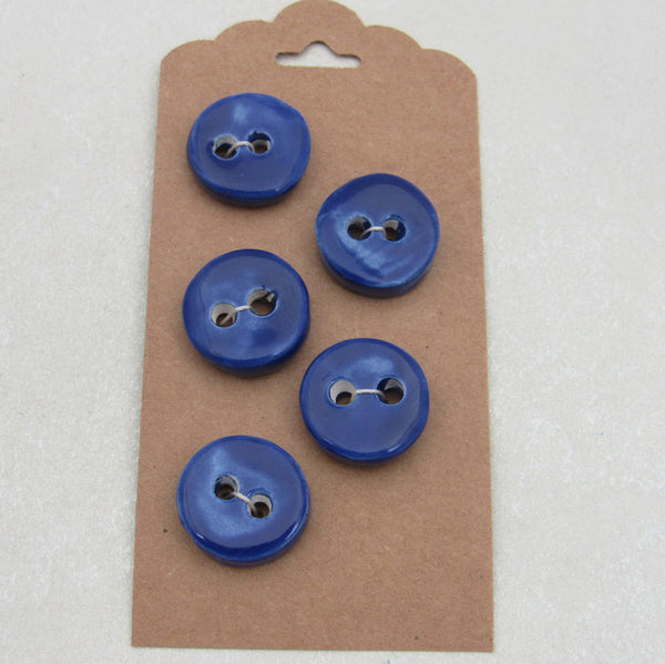 Four blue buttons on a brown cardboard backing with a white background