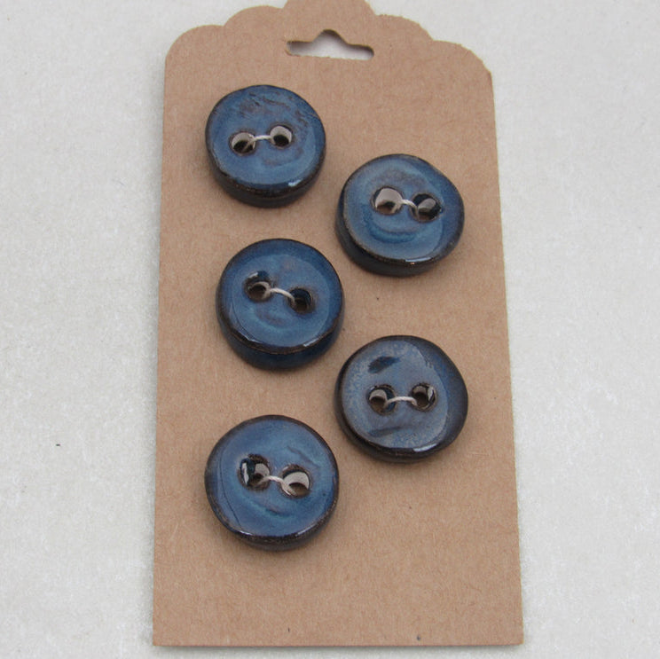 Set of blue buttons on a cardboard backing against a white background