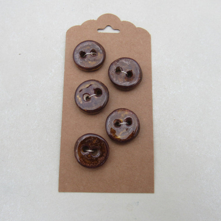 Five brown buttons on a cardboard backing against a white background