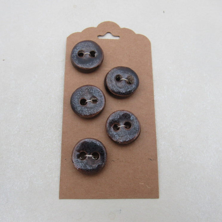 Four dark blue buttons on a cardboard backing against a white background