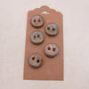 Set of five rust-colored buttons on a brown cardboard backing against a light pink background