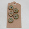 Set of four ceramic buttons with a greenish patina on a cardboard backing.