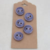 Set of five purple buttons on a cardboard backing against a white background