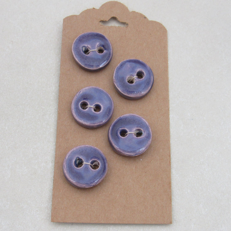 Set of five purple buttons on a cardboard backing against a white background