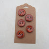 Set of five red buttons on a brown cardboard backing against a white background