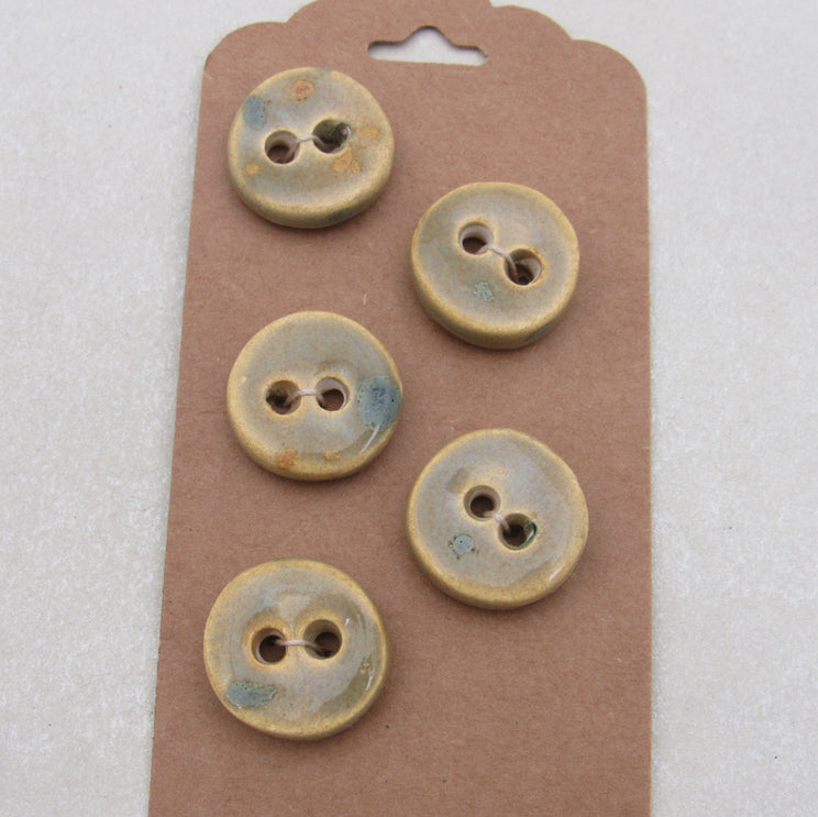Five ceramic buttons on a brown card with a white background