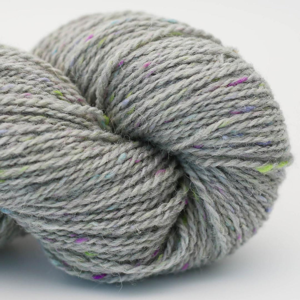 Close-up of a skein of gray yarn with speckles on a light background