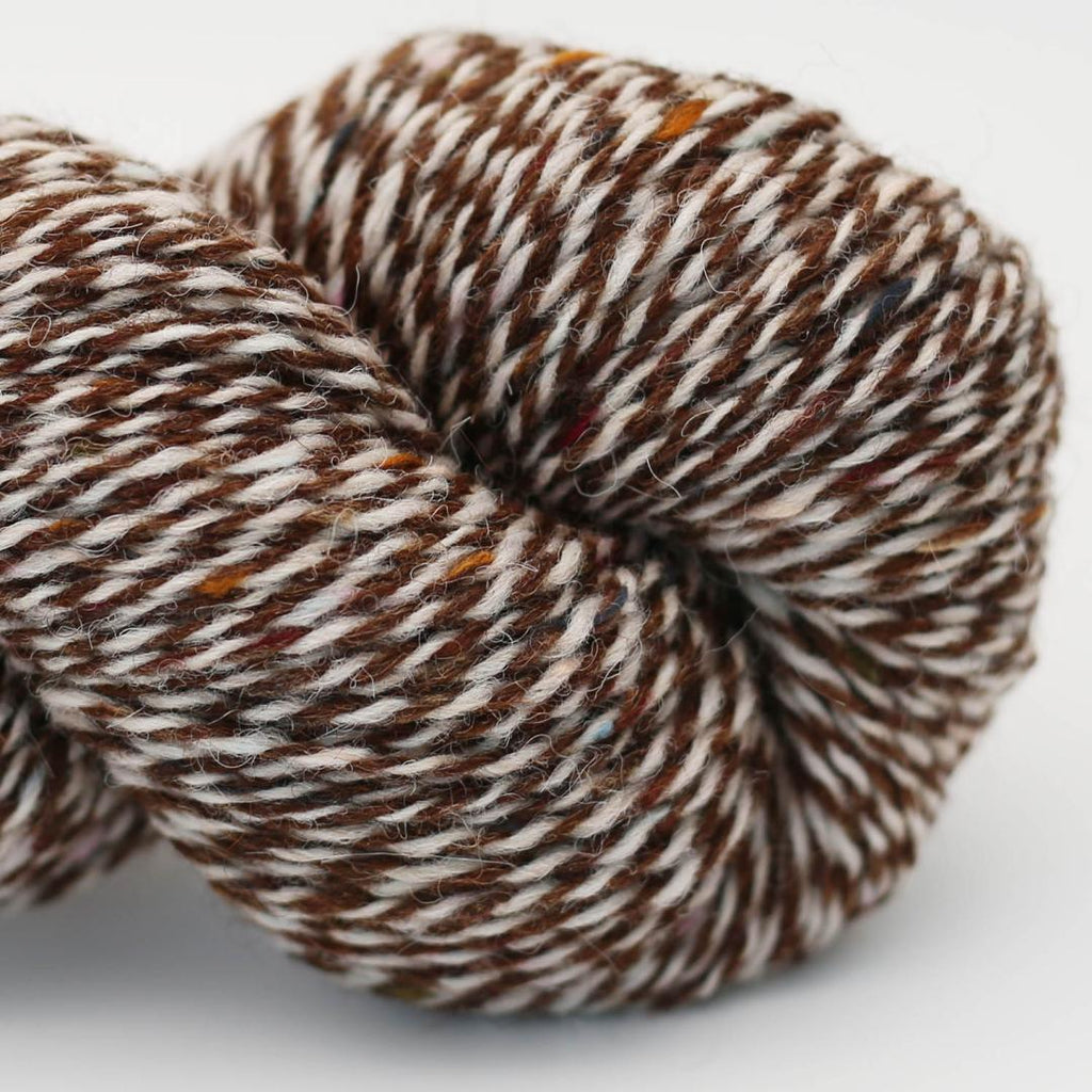 Close-up of a skein of brown and white yarn on a light gray background