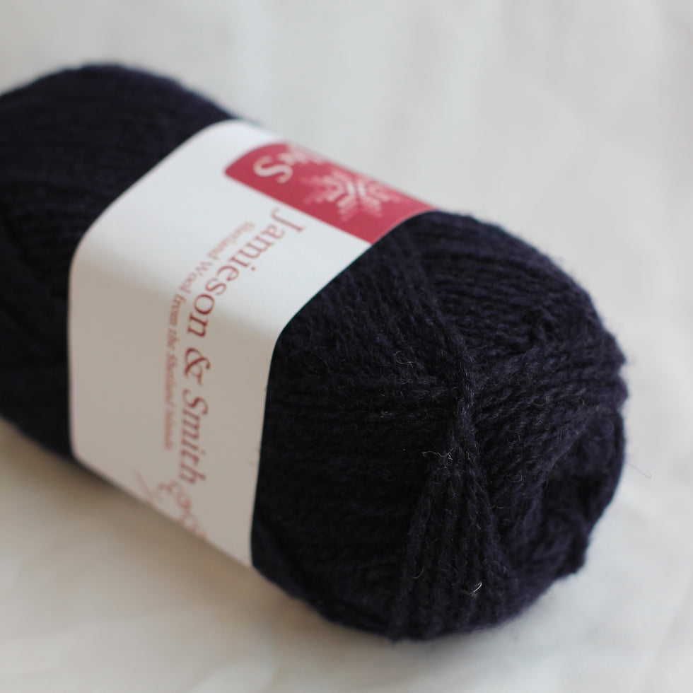 Ball of dark yarn with a label on a light background