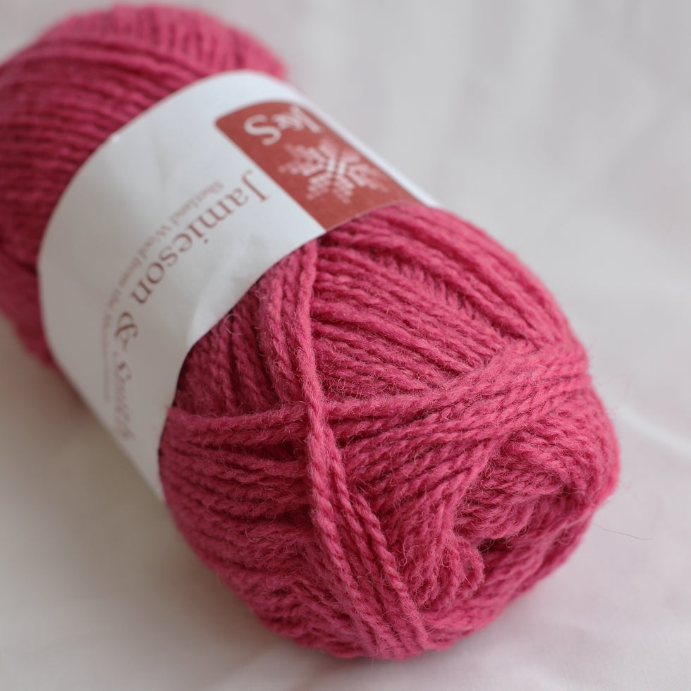Ball of pink yarn with a label on a light background