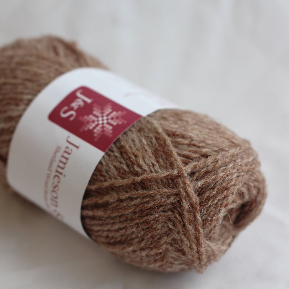 Ball of brown yarn with a label on a white background