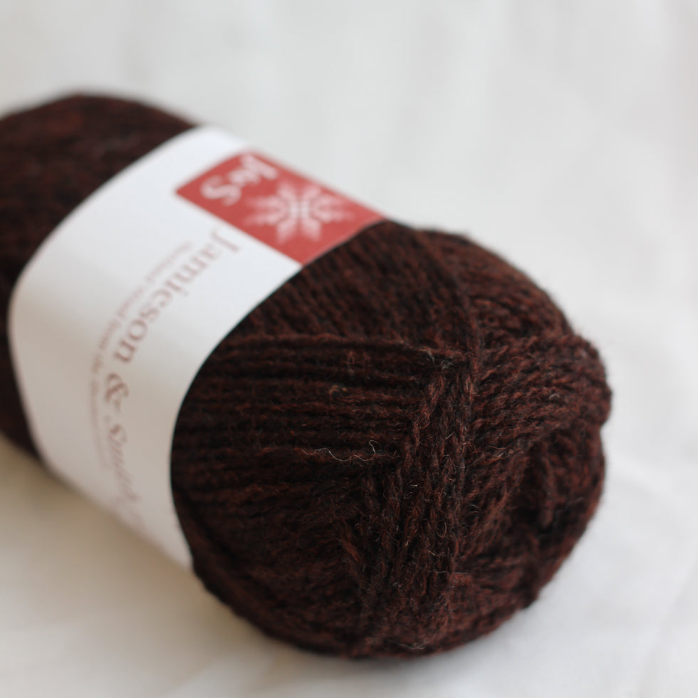 Ball of brown yarn with a label on a white background