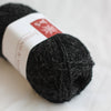 Ball of black yarn with a label on a white background
