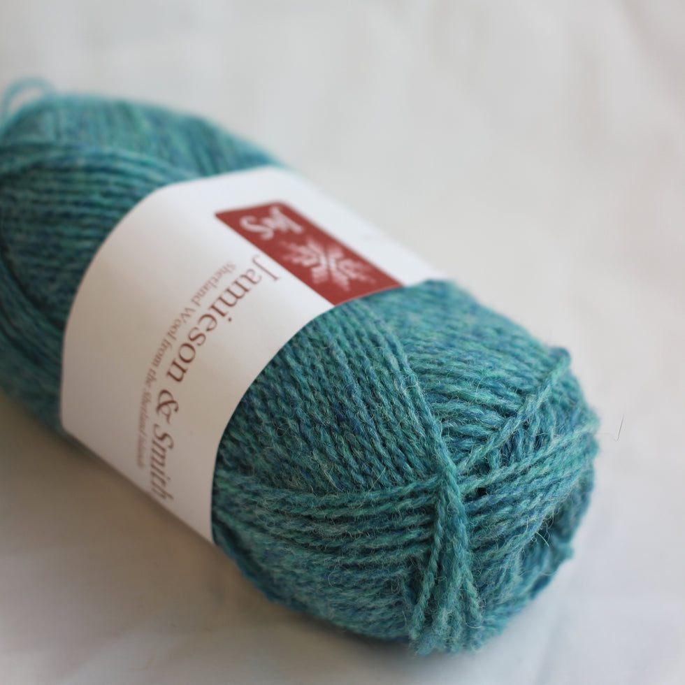 Teal skein of yarn with a label on a light background