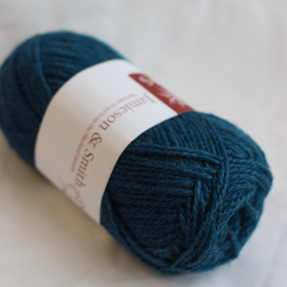 Teal skein of yarn with a label on a light background