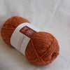 Ball of orange yarn with a label on a white background