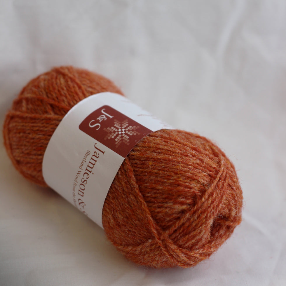 Ball of orange yarn with a label on a white background