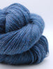 A close-up of a skein of textured yarn in a heathered medium-to-dark blue color, showing the fuzzy, twisted fibers against a clean white background.