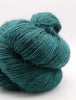 A close-up of a skein of teal yarn with a soft, fuzzy texture on a light gray background.
