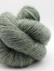 Close-up of a skein of green yarn on a white background