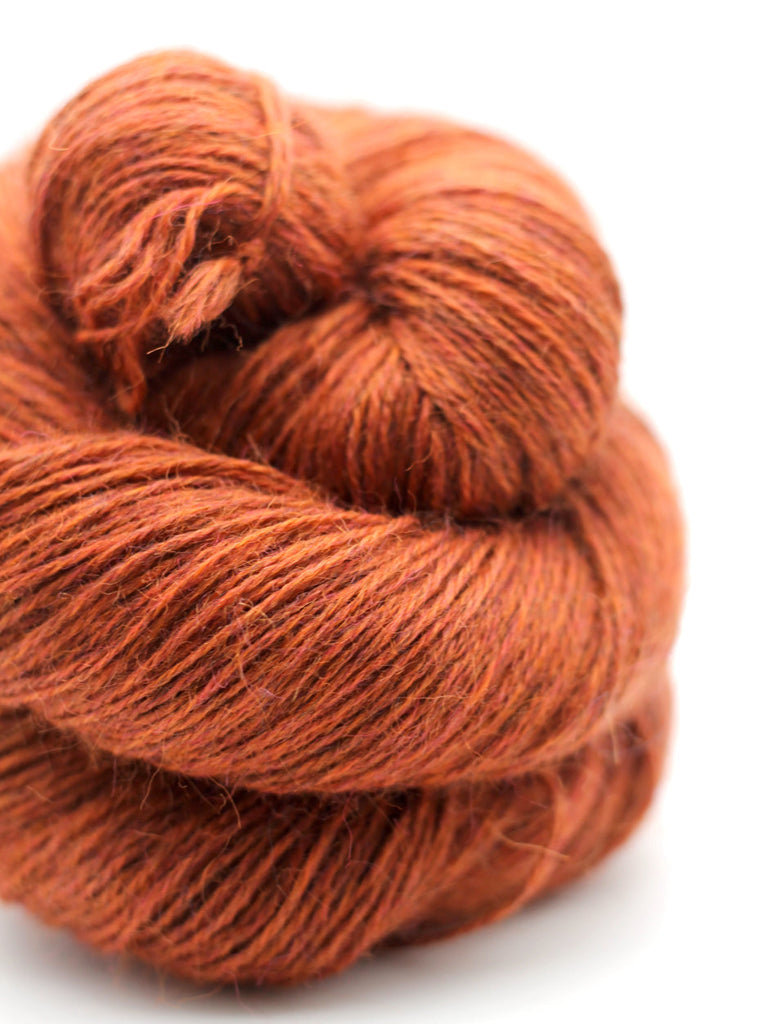Close-up of a skein of orange yarn on a white background