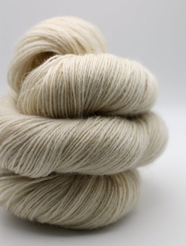 1 skein of soft, cream-colored yarn stacked together on a light gray background.