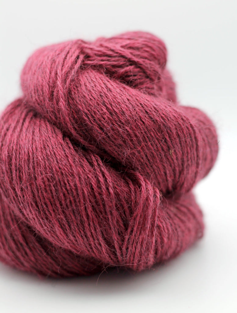 A close-up of a skein of textured yarn in a deep berry pink color, set against a clean white background.