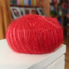Red yarn ball on a white surface with a blurred background