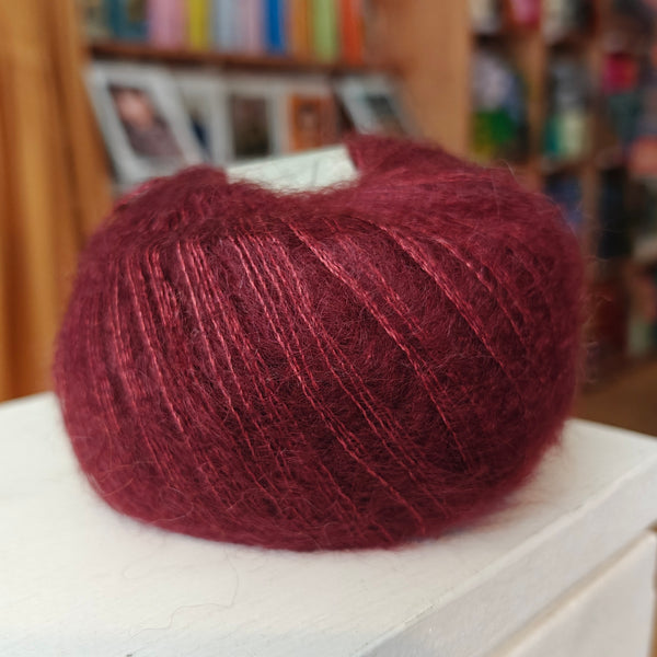 Ball of red yarn on a white surface with a blurred background
