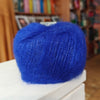 Blue yarn ball on a white surface with a blurred background