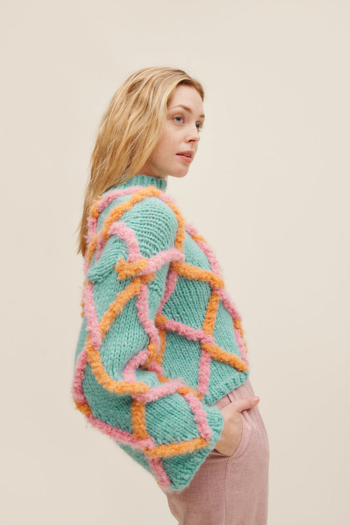 Woman wearing a colorful knitted sweater with a beige background
