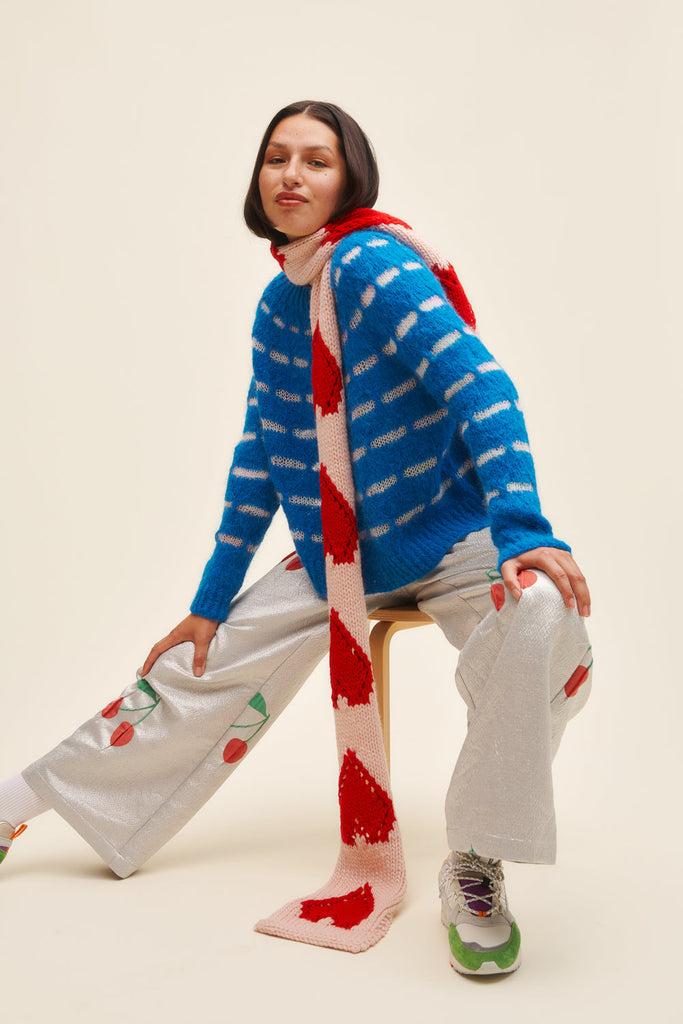 Person wearing a blue and white striped sweater with a matching scarf on a beige background