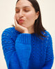 Woman wearing a blue knitted sweater against a beige background