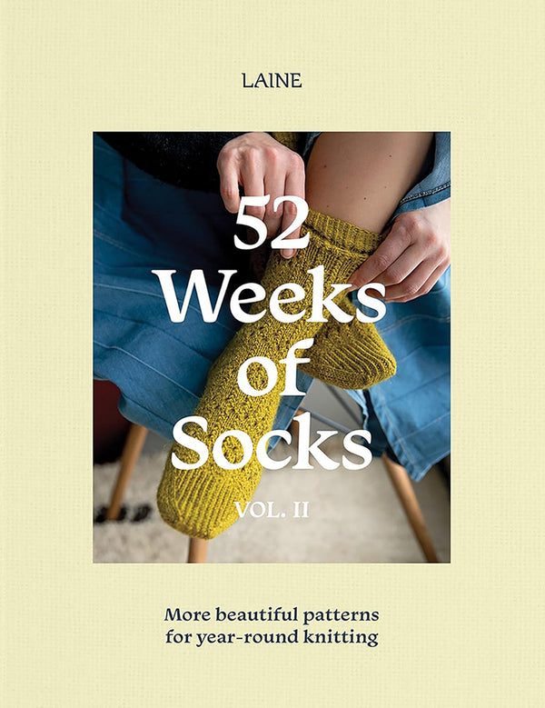 A cover image of the book '52 Weeks of Socks Vol. II', showing a person's hands knitting yellow socks with a title and subtitle 'More beautiful patterns for year-round knitting'.