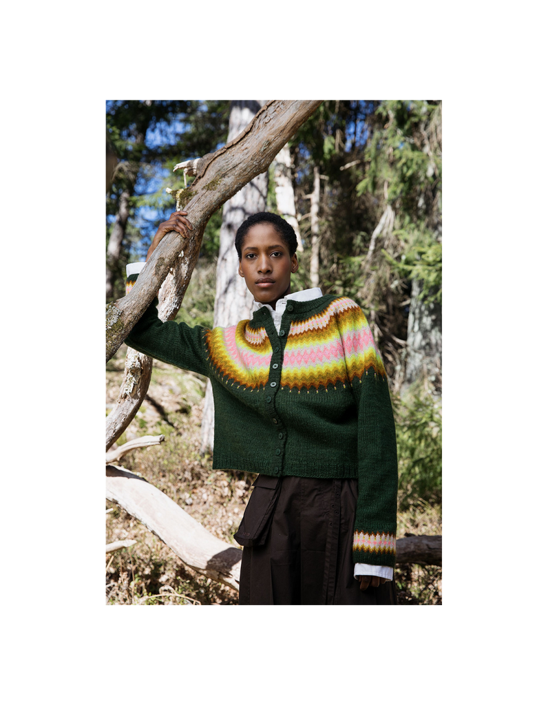 Person wearing a green sweater with a colorful pattern in a forest setting