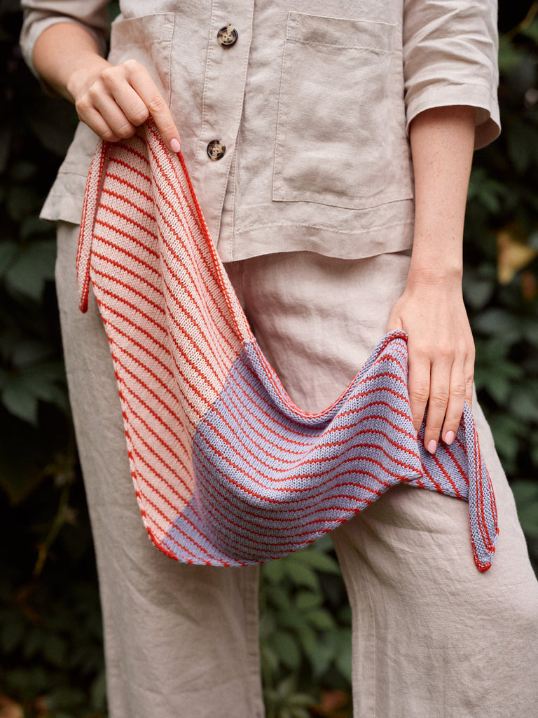 Person holding a striped knitted bag with a natural background