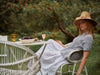 Woman sitting at a table outdoors with a garden setting
