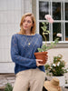Woman in a blue sweater holding a potted plant outdoors