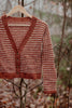 Knitted sweater with a checkered pattern hanging on a branch in a forest setting
