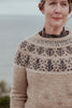 Woman wearing a patterned sweater with a blurred natural background