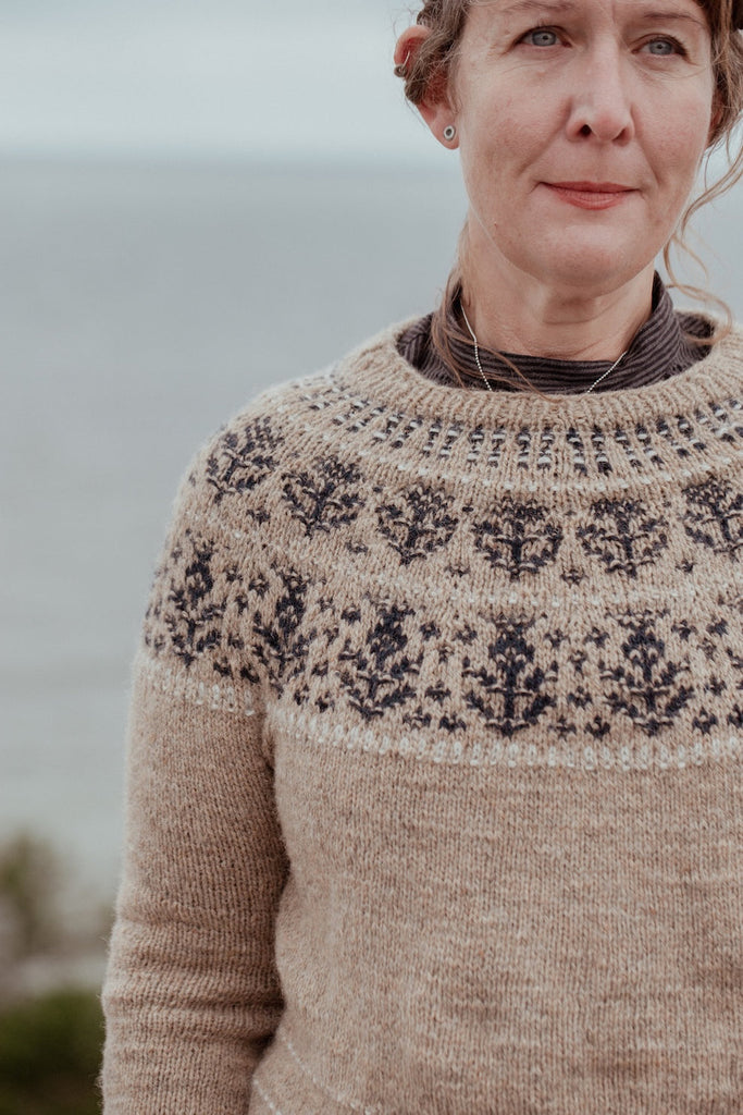 Woman wearing a patterned sweater with a blurred natural background